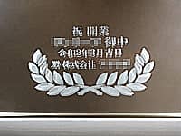 「祝開業、○○御中、令和2年3月吉日、贈 株式会社○○」を彫刻した、開業祝い用の鏡