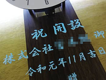 �c�Ə��J�ݏj���p�̊|�����v�̑O�ʃK���X�ɒ��������u���j�����b�Z�[�W�A�����̉�Ж��A�J�ݓ��̓��t�v���A�V���o�[�ɒ��F�����������̃N���[�Y�A�b�v�摜