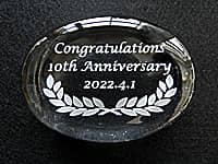 「Congratulations 10th Anniversary、表彰日の日付」を彫刻した、勤続10年表彰の記念品用のガラス製ペーパーウェイト