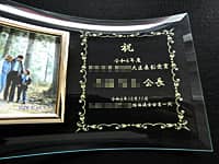 受賞内容、受賞者名、受賞日の日付を彫刻した、受賞記念品用のガラス製写真立て
