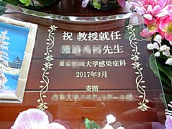 「祝教授就任 ○○先生、○○医科大学○○科」を彫刻した、教授就任祝いの贈り物用のガラス製写真立て