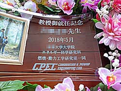 「教授御就任記念 ○○先生、研究室のロゴ」を彫刻した、教授就任祝いの贈り物用のガラス製フォトスタンド