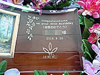 「Congratulations on your 60th birthday、○○様」「会社のロゴマーク」を彫刻した、社員への還暦祝い用のガラス製写真立て