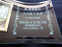 「お祝いメッセージ、先生の名前、日付」を彫刻した、教授就任祝い用の写真立て