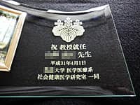 「校章」と「祝教授就任、○○先生、○○大学○○研究室一同」を彫刻した、教授就任祝い用の写真立て