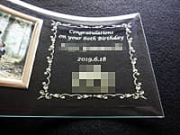 「Congratulations on your 60th birthday. 名前、日付」と「会社のロゴマーク」を彫刻した、社員への還暦祝い用の写真立て