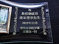 「祝教授御就任 ○○先生、日付、○○大学医学部○○研究室一同」を彫刻した、教授就任祝い用のフォトスタンド