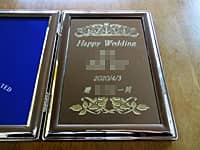 「Happy wedding、新郎と新婦の名前、2020/4/3、贈○○一同」を彫刻した、結婚祝い用のブックタイプのフォトフレーム