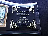 教授就任祝い用のフォトスタンド(祝教授ご就任 ○○先生 ○○大学○○部一同を、ガラス製のフォトスタンドに彫刻)