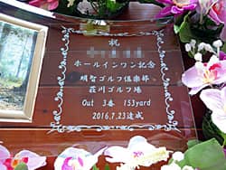「祝 ホールインワン記念、達成者名、達成日」を彫刻した、ホールインワンの記念品用のガラス製写真立て