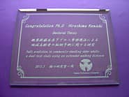 「Congratulations、名前、論文のテーマ、大学のマーク」を彫刻した、博士論文発表の記念品用のガラス盾