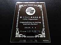 「会社の名前とマーク、Congratulations on starting your new business、贈り主の名前」を彫刻した、会社の設立祝い用のガラス盾