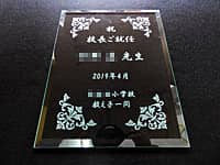 「祝校長ご就任 ○○先生」を彫刻した小学校の校長就任祝い用のガラス盾