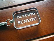 永年勤続者の名前と会社名を彫刻した、永年勤続の記念品用のガラス製ストラップ