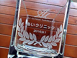 クリニックのロゴマークを側面に彫刻した、開院祝い用のフラワーベース