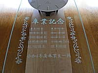 「卒業記念、卒業生全員の名前、令和4年度卒業生一同」を前面ガラス部に彫刻した、卒業生から小学校へ寄贈する掛け時計