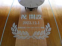 「祝開設、開設日の日付、贈り主の会社名」を前面ガラスに彫刻した、支店開設祝い用の壁掛け時計