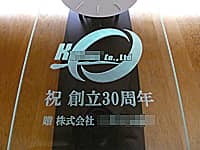 �����̉�Ђ̃��S�}�[�N�A�j �n��30���N�A�����̉�Ж���O�ʃK���X�ɒ��������A���N�j���p�̕Ǌ|�����v