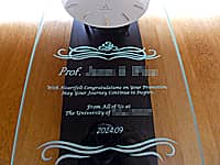 前面ガラスに、新教授の名前、お祝いメッセージ、贈り主の名前、就任日の日付を彫刻した、教授就任祝い用の壁掛け時計