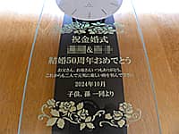 「祝金婚式、両親の名前、結婚記念日の日付、贈り主の名前」を前面ガラスに彫刻した、両親の金婚式祝い用の壁掛け時計